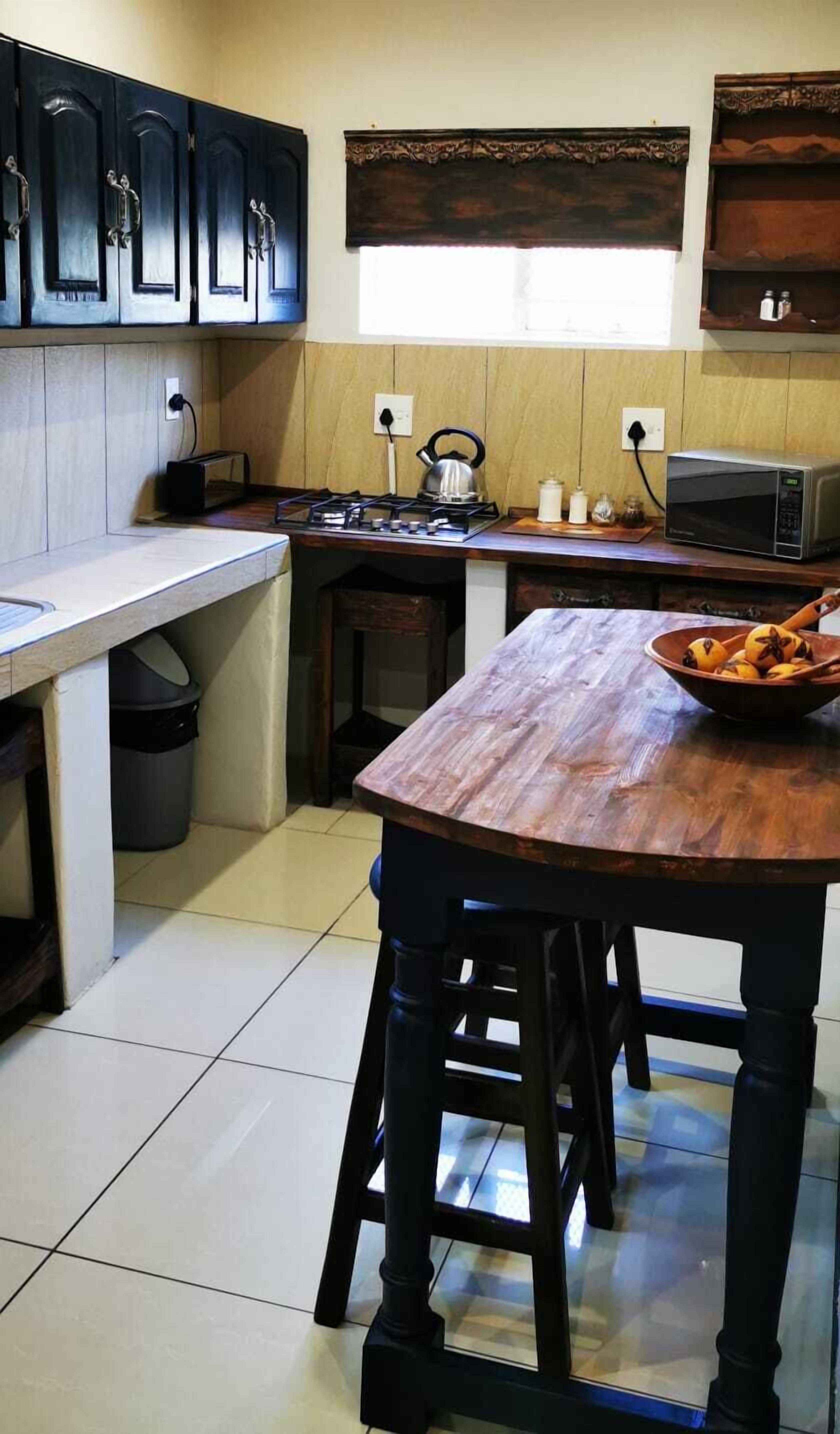 A compact kitchen with a wooden countertop, a gas stove, a microwave, and cabinets.