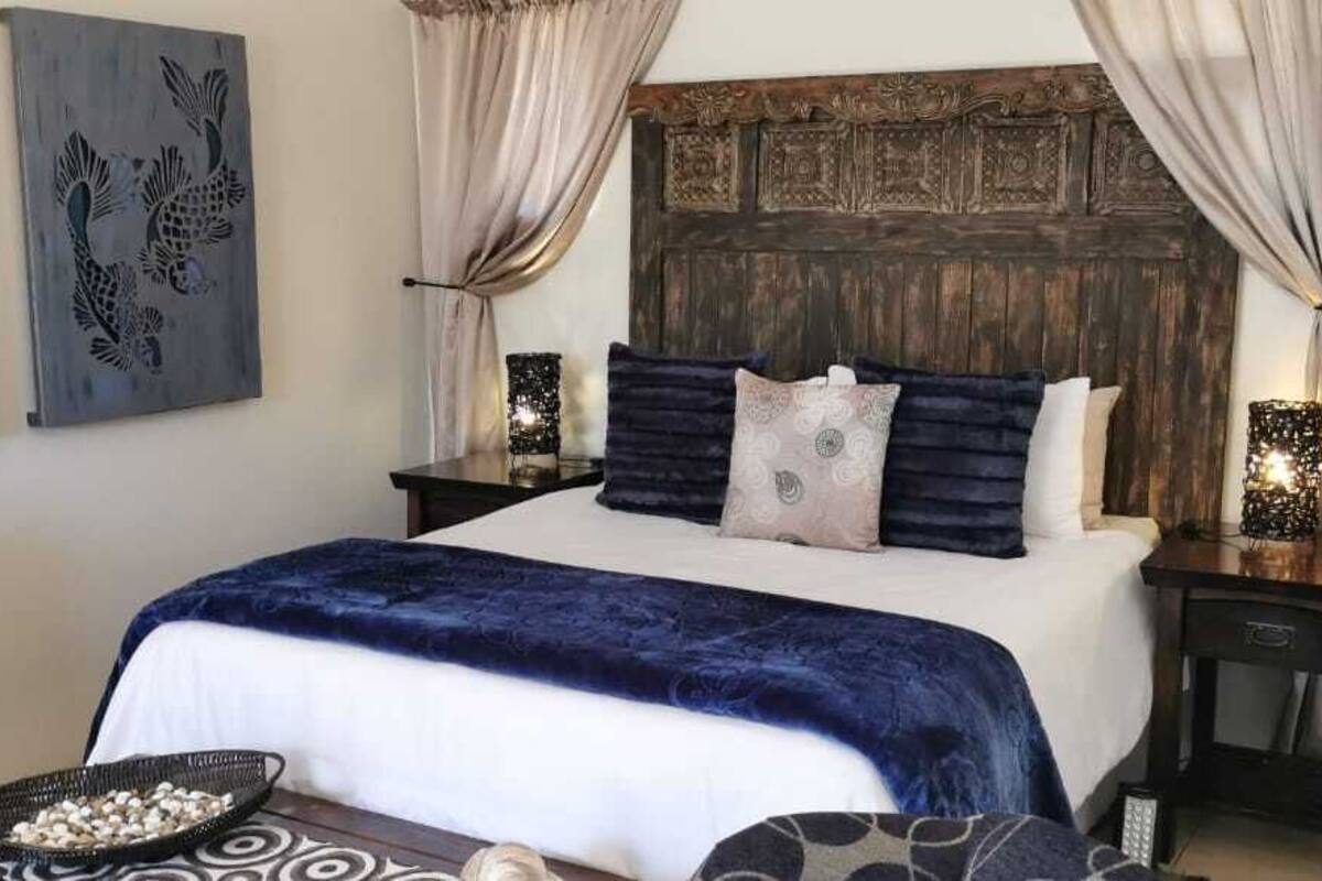 A bedroom with a large bed, dark blue bedding, and two nightstands with lamps.