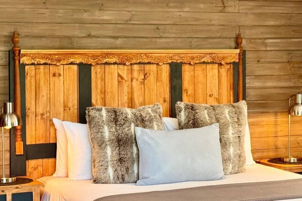 A wooden-paneled bedroom with a bed, multiple pillows, and two bedside lamps.