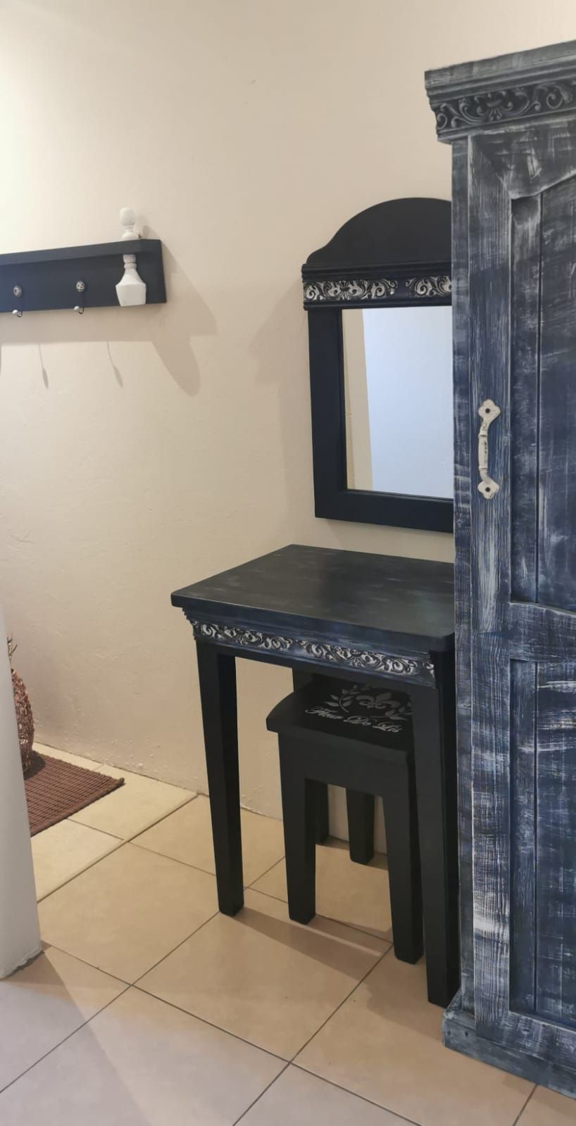Una habitación con un escritorio de madera oscura, una silla y un armario con espejo.