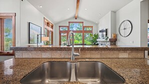 Cocina con pileta doble, encimera de granito y vistas al exterior a través de amplias ventanas.