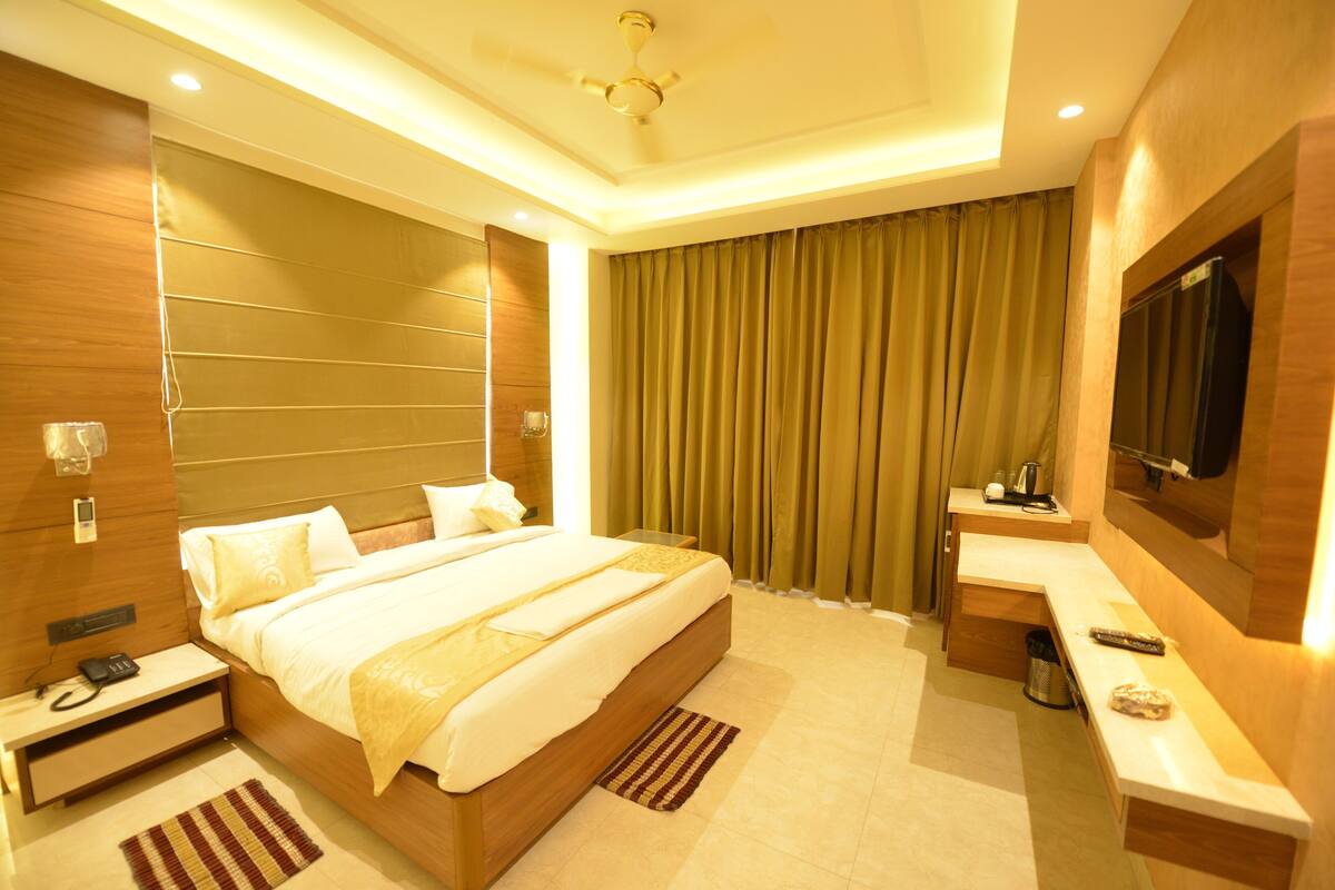A modern hotel room with a large bed, a desk, a television, and a bathroom.