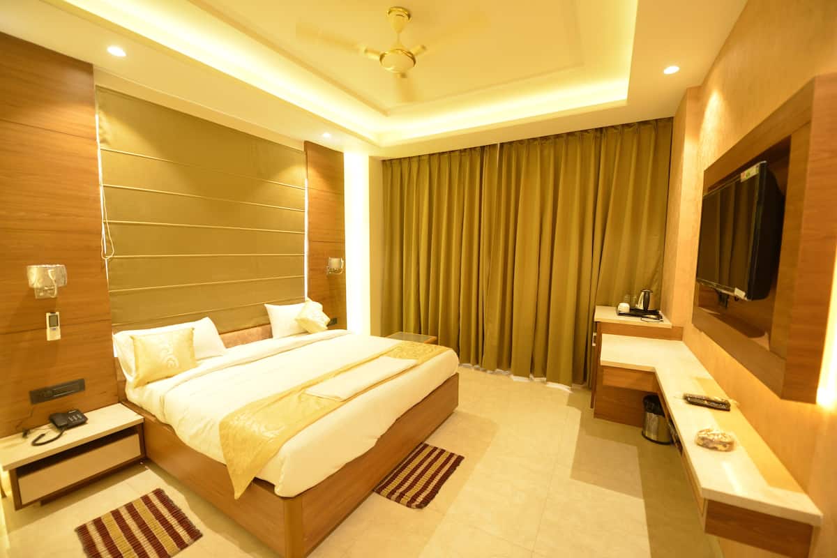 A modern hotel room with a large bed, a desk, a television, and a bathroom.