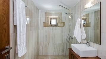 A modern bathroom with a glass-enclosed shower, a wooden vanity with a white sink, and a large mirror.