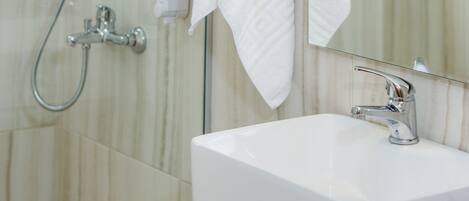 Ein modernes Badezimmer mit Duschkabine aus Glas, einem weißen Waschbecken und einem Spiegel.