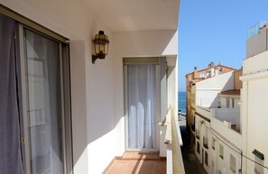 Un balcon étroit donnant sur la mer, une porte avec un rideau et un luminaire fixé au mur.