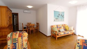 A living room with a wooden dining table, chairs, a sofa, and a cabinet. - PUIG SUREDA 13-2B (L'Escala)