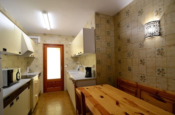 Une cuisine de taille réduite avec une table en bois, un four à micro-ondes, un évier et des placards.