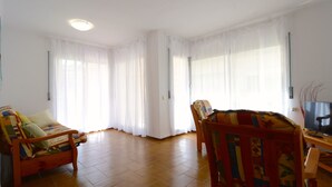 A living room with a sofa, a chair, a TV, and a wooden table. - PUIG SUREDA 13-2B (L'Escala)