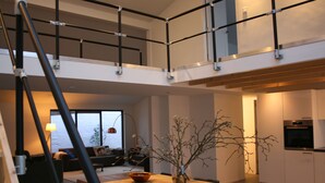 A modern kitchen with a wooden table, a vase with branches, and a view of the sea through large windows. - Spacious house & spa near forest, beach and sea and the cozy village of Bergen (Bergen)
