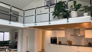 A modern loft-style apartment with a dining area, kitchen, and a balcony with plants. - Spacious house & spa near forest, beach and sea and the cozy village of Bergen (Bergen)