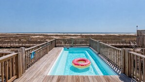 En træterrasse med en pool og en lyserød oppustelig ring.