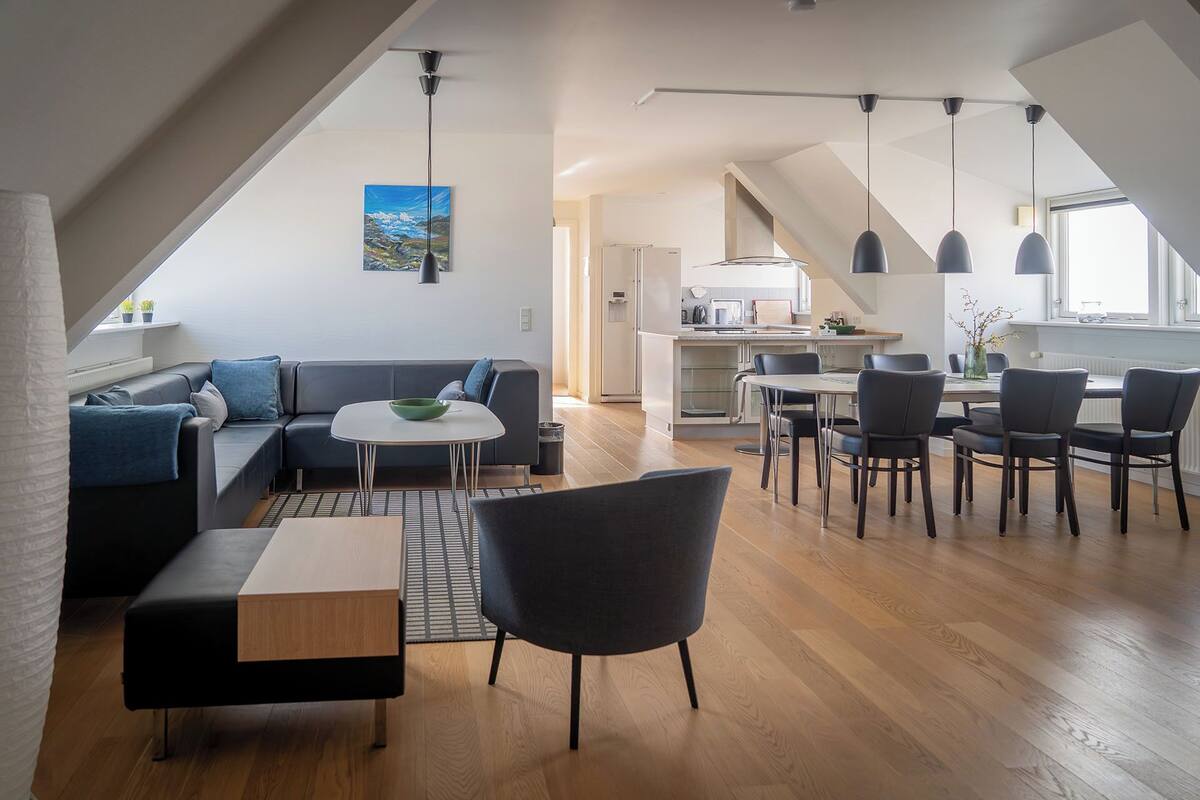 A modern loft apartment with a dining area, kitchen, and living space.