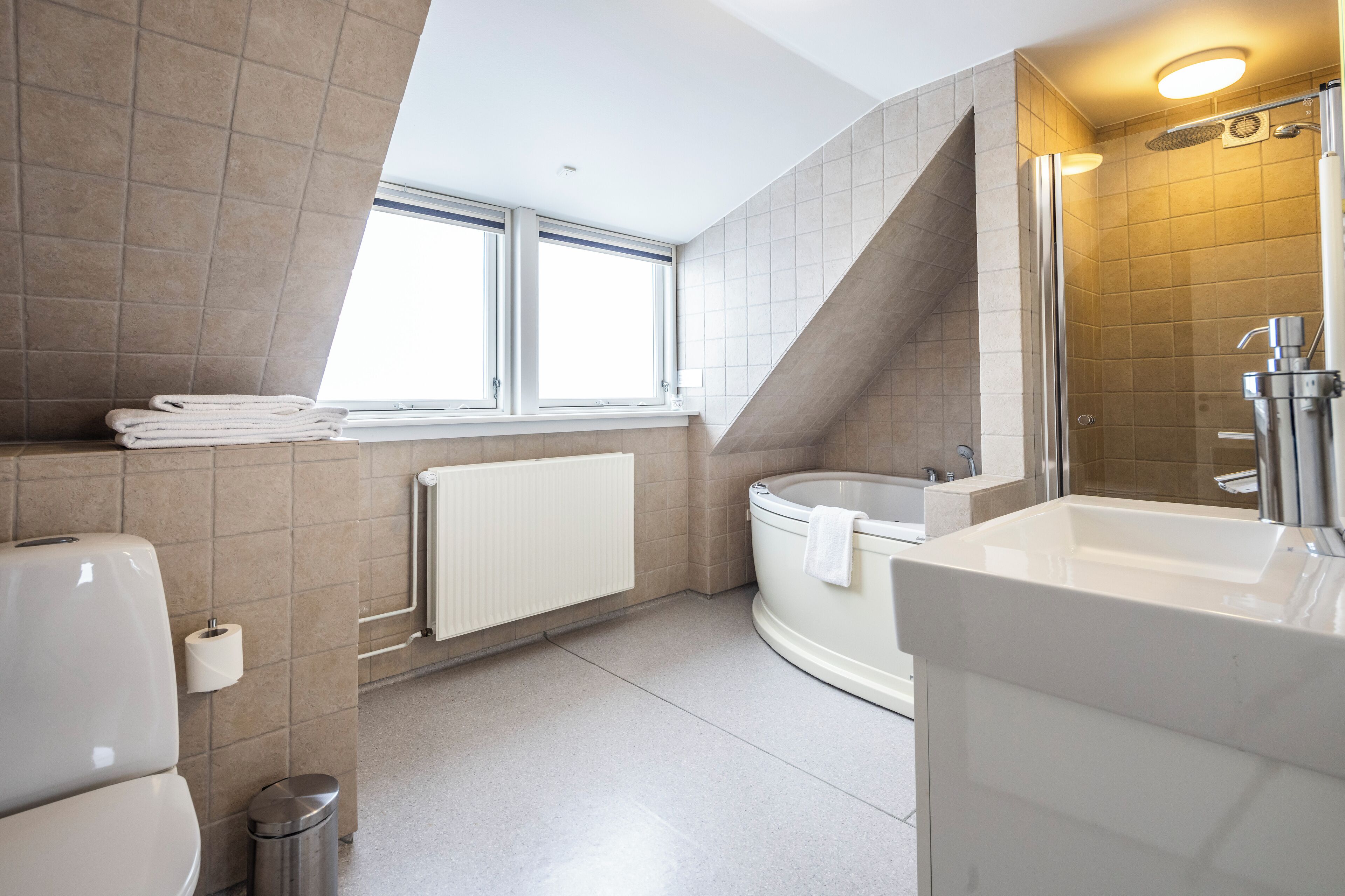 Een moderne badkamer met een bad, een douche en een wastafel.