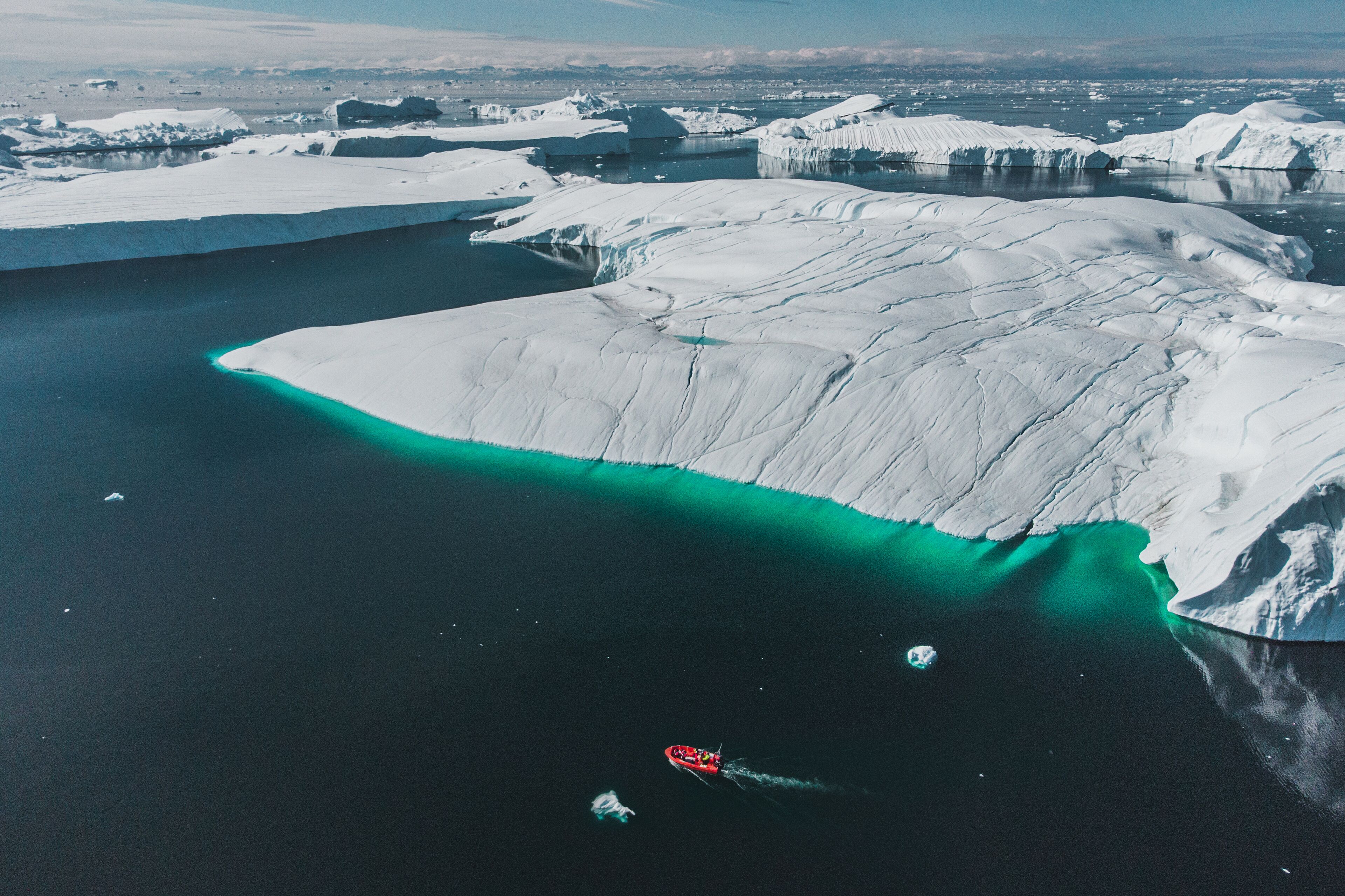 Vista aérea de un gran iceberg con un canal de agua turquesa cristalina.