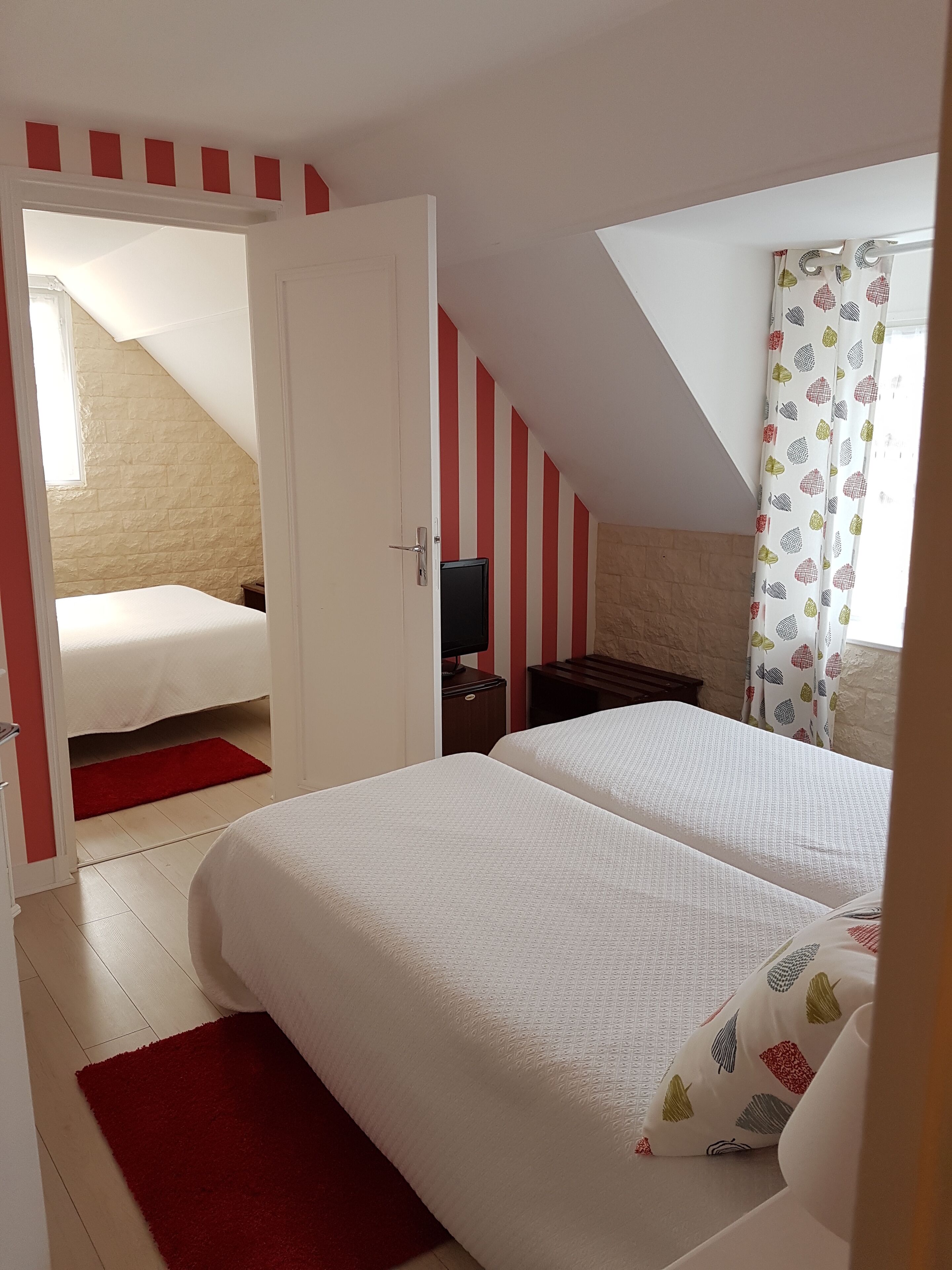 Une chambre avec deux lits, une télévision et une fenêtre avec des rideaux.
