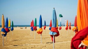 Ein Strand mit mehreren Reihen bunter Sonnenschirme.