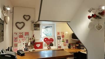 A kitchen with a wooden countertop, heart-shaped decorations, and a window with a view of greenery.