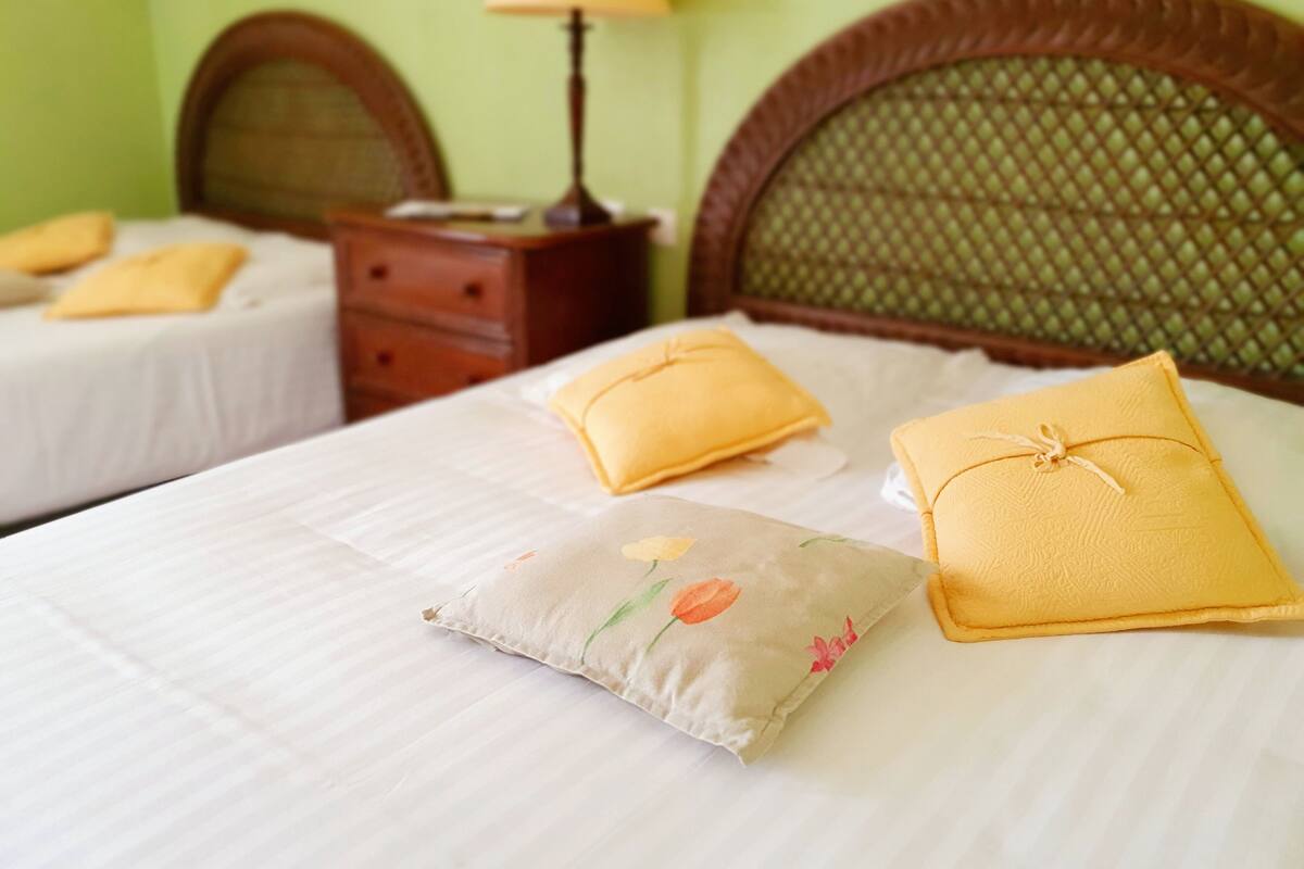 Een hotelkamer met twee bedden, elk voorzien van een houten hoofdbord en een nachtkastje.