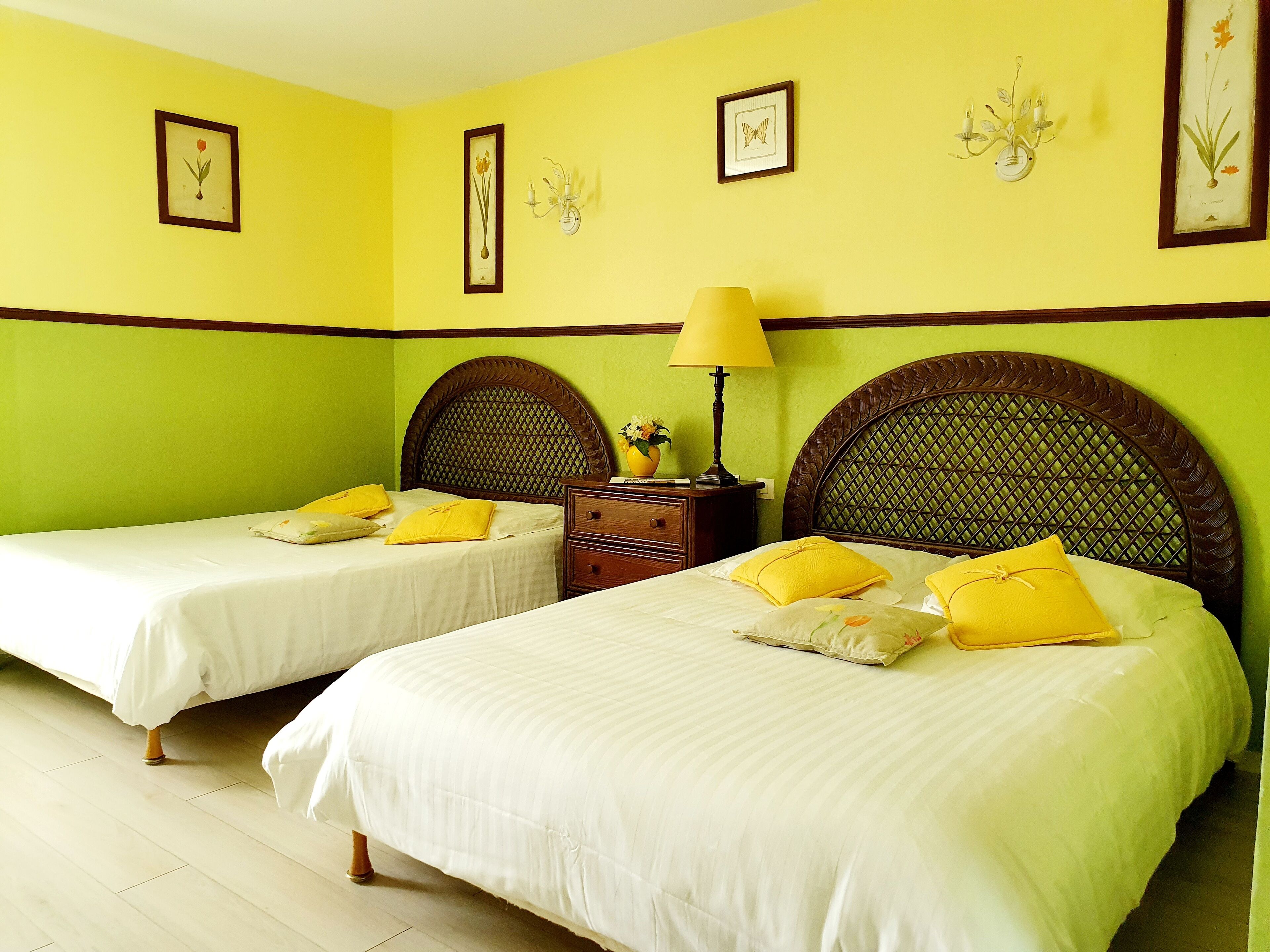 A hotel room with two beds, each with a wooden headboard, a nightstand, and a lamp.