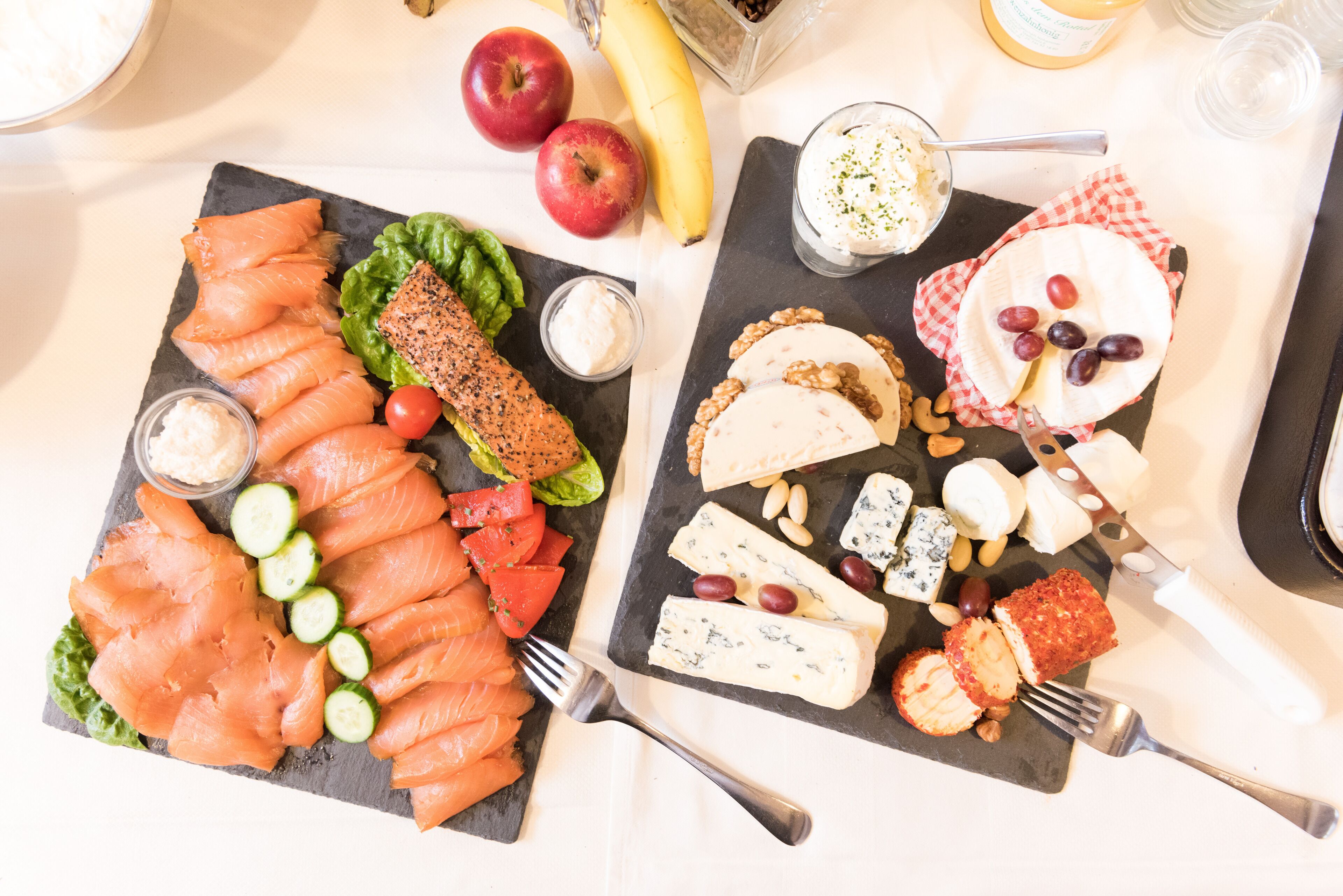 A charcuterie board with various cheeses, fruits, and smoked salmon.