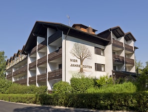 Un hotel de varios pisos con balcones y un mural de un árbol en la fachada.