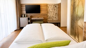 Une chambre d’hôtel équipée d’un lit, d’un bureau, d’une télévision et d’un mur orné d’un motif décoratif.