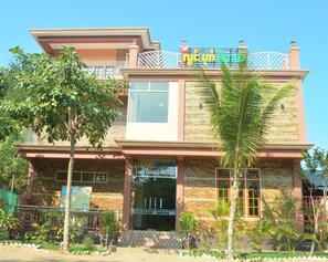 Un motel à deux étages, doté d’une façade en pierre, de grandes fenêtres et d’un balcon.
