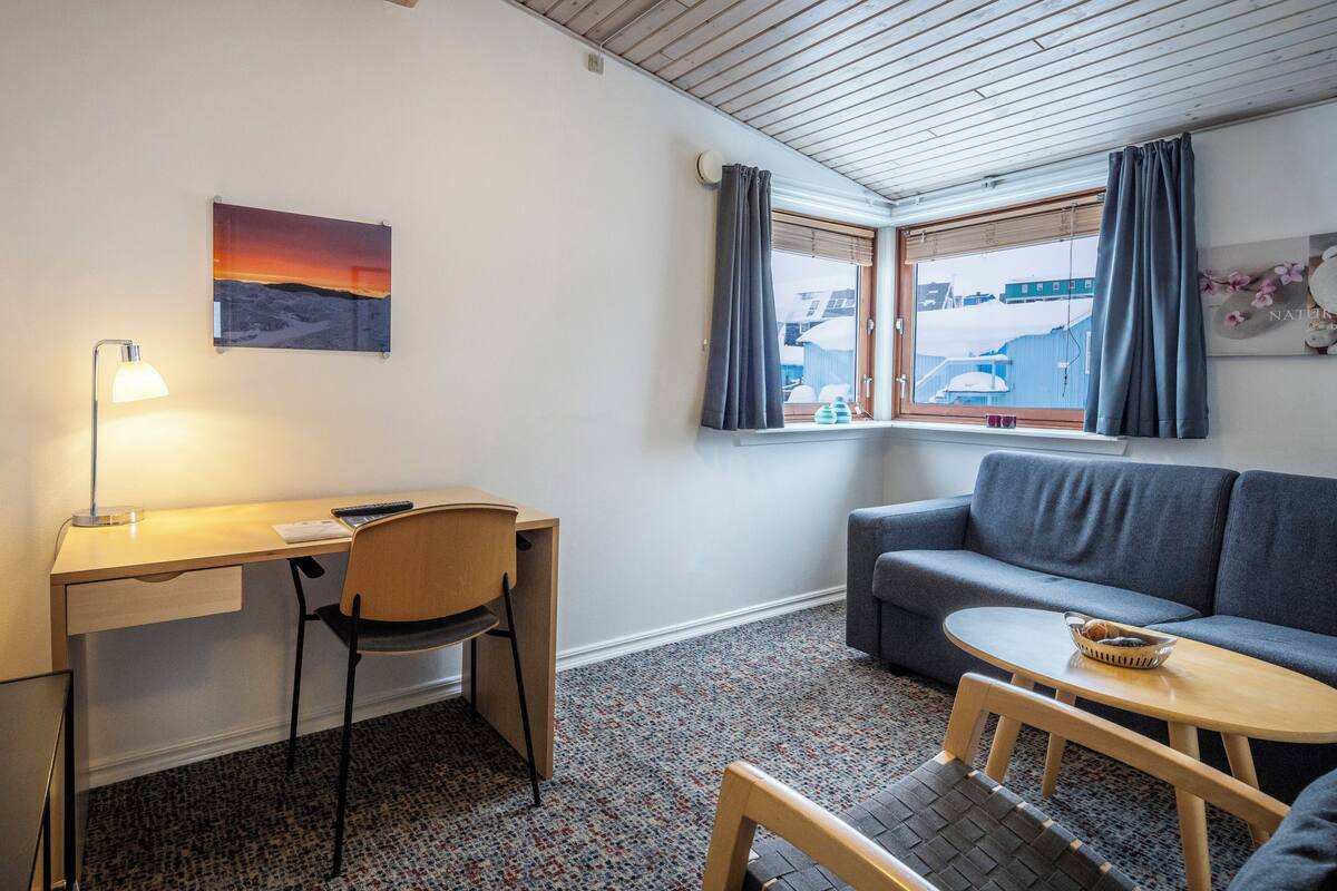 Une pièce comprenant un bureau, une chaise, un canapé et une petite table.