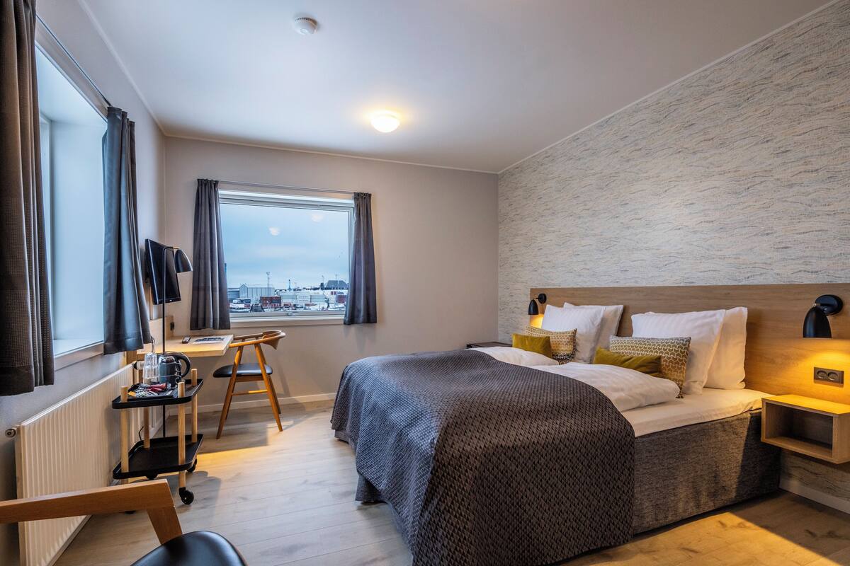 Une chambre d’hôtel moderne, dotée d’un grand lit, d’un bureau et offrant une vue sur la ville.