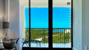 A room with a large sliding glass door leading to a balcony with a view of a beach and ocean. - Updated Beachfront Getaway ~Steps to World-Class Shelling, Resort Amenities, Dining, Shops & WiFi (Marco Island)