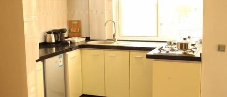 A compact kitchen with a sink, a stove, and cabinets.