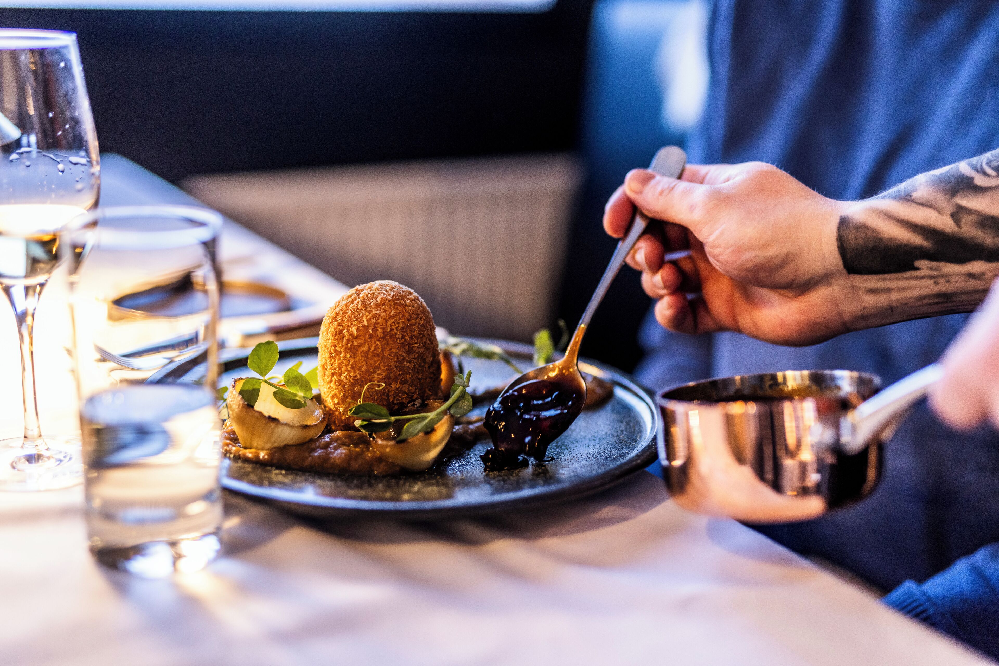 Ein Esstisch mit einem Teller Essen, einem Glas Wasser und einer Metalltasse.