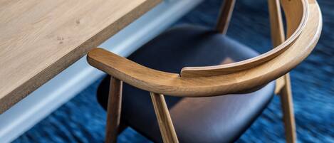 A wooden chair with a curved backrest and a dark cushion, positioned next to a wooden table.