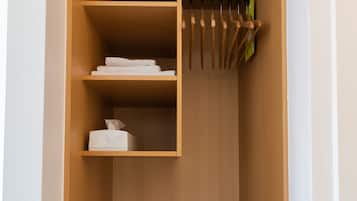 A wooden closet with shelves, a hanging rod, and a black mat at the bottom.