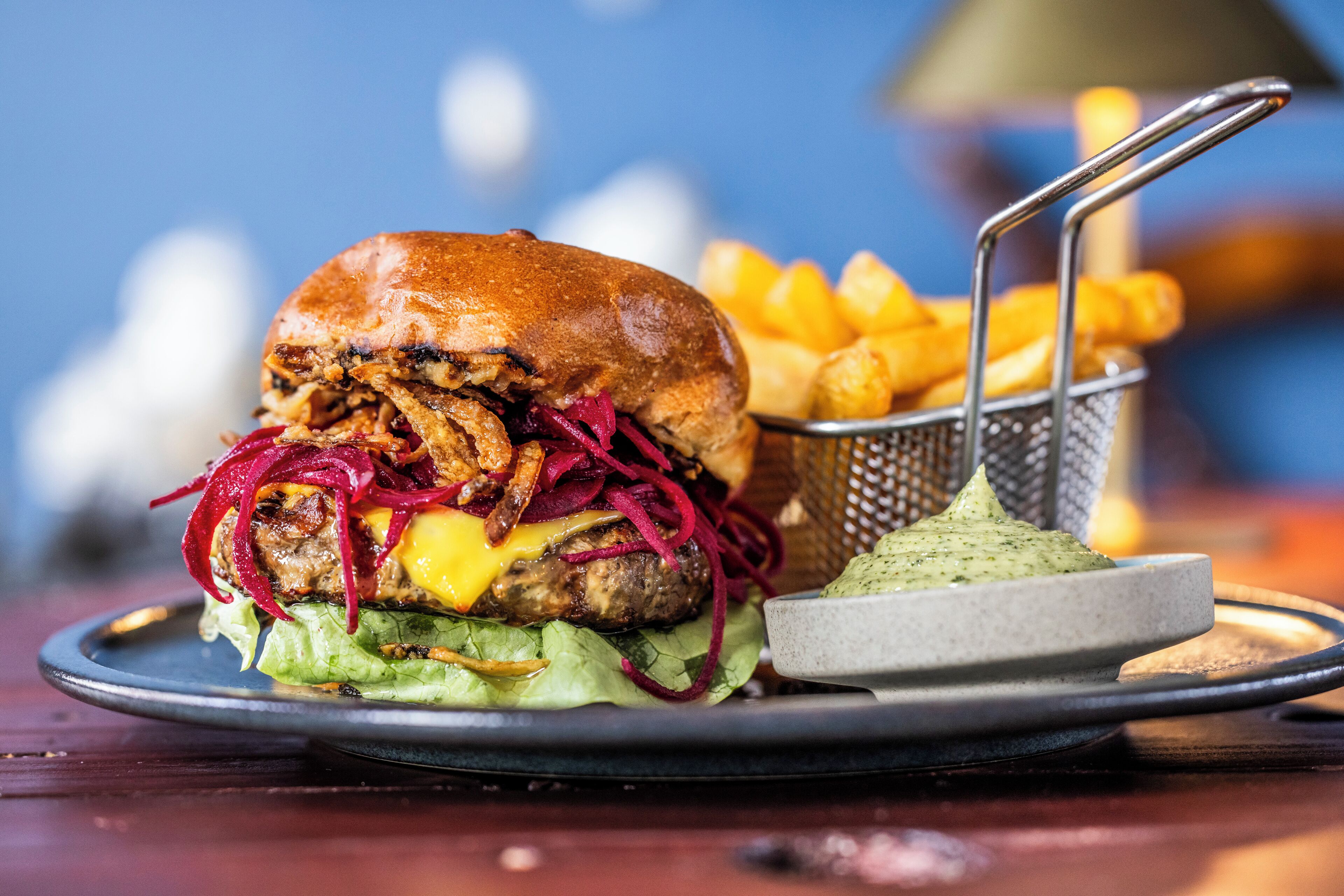 A burger with fries and a dipping sauce on a plate.