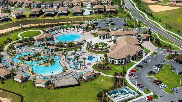 Eine Vogelperspektive zeigt ein Resort mit mehreren Schwimmbecken, einem Golfplatz und einem Parkplatz.