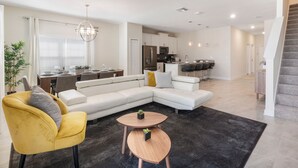 Ein modernes Wohnzimmer mit einem Ecksofa, einem gelben Sessel und einem runden Couchtisch.