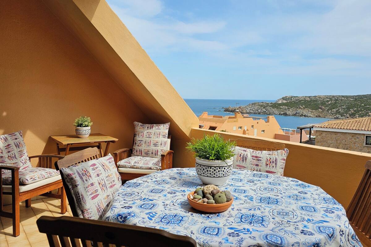 Ein Balkon mit Tisch, Stühlen und Topfpflanzen.