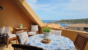 Un balcon avec une table, des chaises et des plantes en pot.