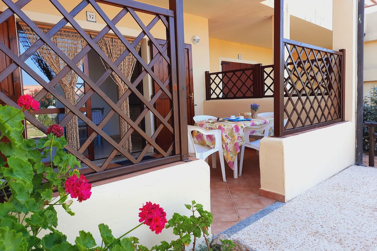 A balcony with a table set for dining, a view of the interior, and a decorative fence.