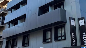 Un moderno edificio de hotel con letrero que dice "HOTEL UVE MARCENADO", múltiples balcones y cielo despejado.