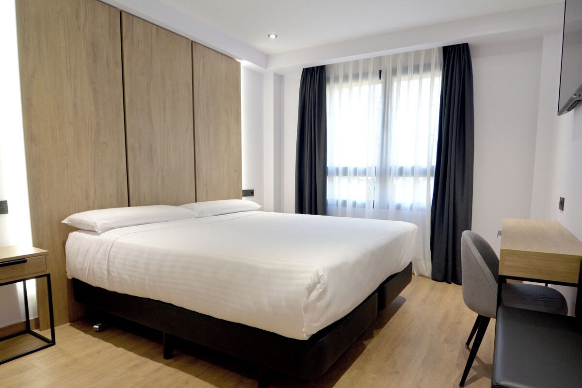 Une chambre d’hôtel moderne avec un grand lit, un bureau et une chaise.