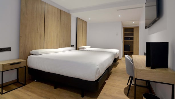 Una habitación de hotel moderna con una cama grande, un escritorio y un televisor.