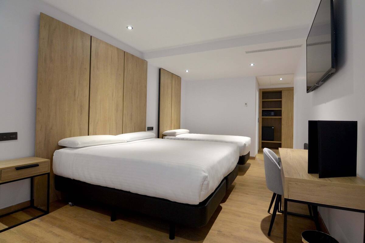 A modern hotel room with a large bed, a desk, and a TV.