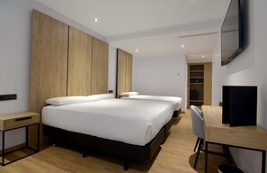 A modern hotel room with a large bed, a desk, and a TV.