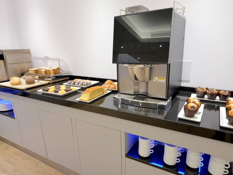 En morgenmadsbuffet med forskellige bagværk, muffins og en kaffemaskine.