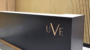 Una mesa de recepción con superficie negra y letras doradas que indican “UVE HOTELS”.