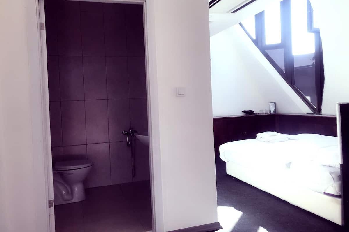 Une chambre d’hôtel avec une salle de bain, un lit et un escalier menant à un étage supérieur.