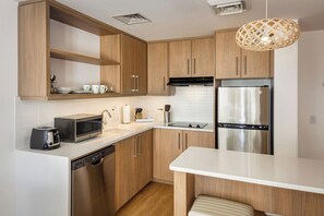 Una cocina moderna con armarios de madera, un refrigerador de acero inoxidable, un microondas y un lavavajillas.